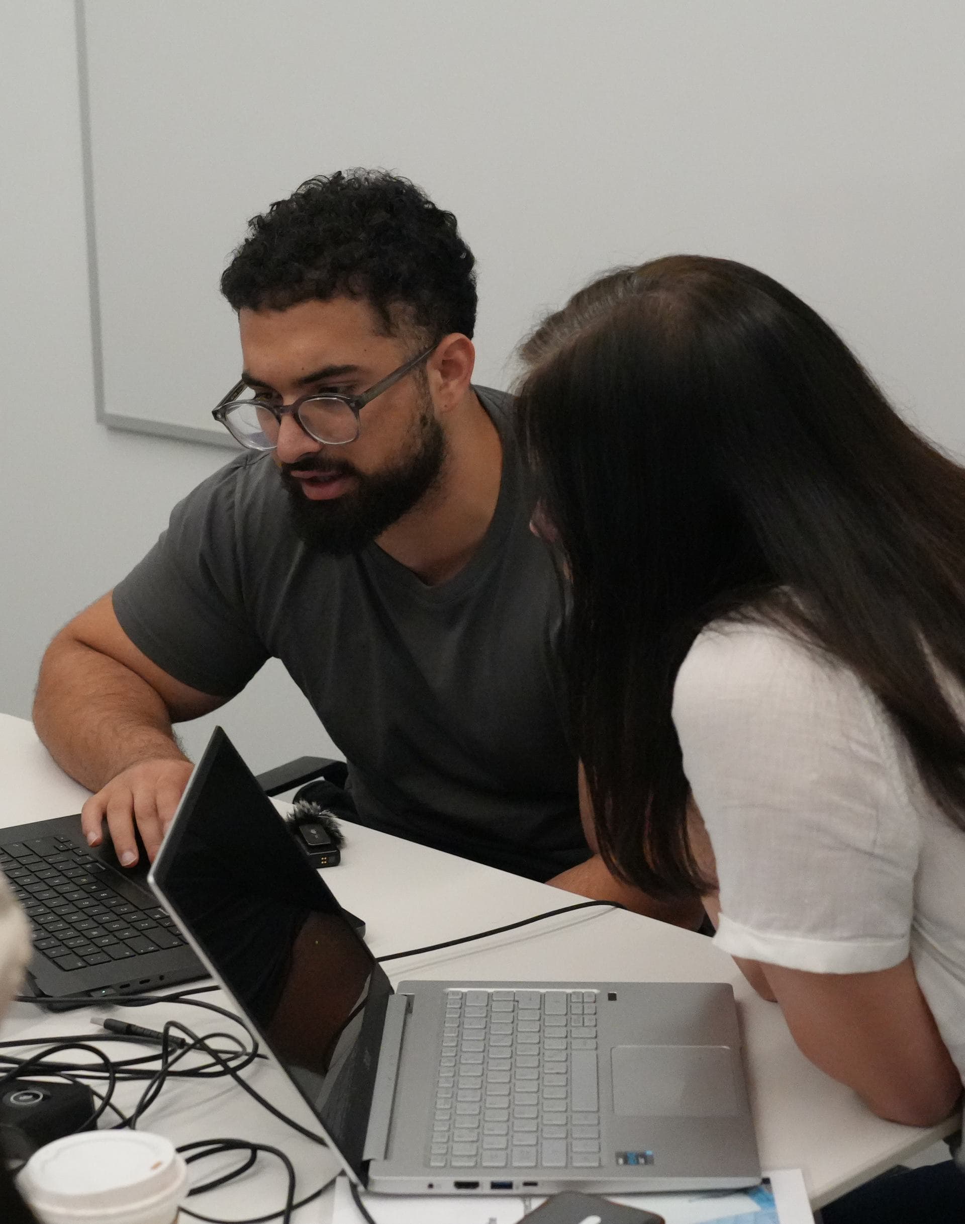 An instructor leaning in to help an attendee at her laptop during a Zero to Agent working session