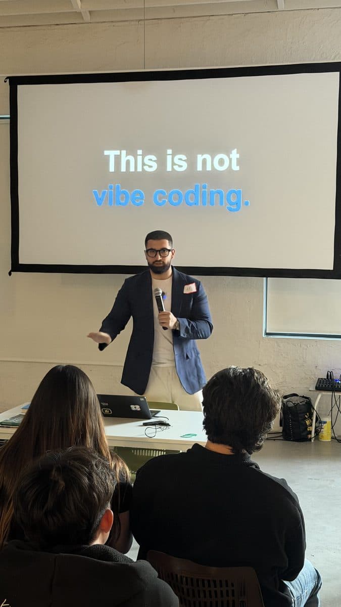 Speaker on stage in front of a slide reading “This is not vibe coding”
